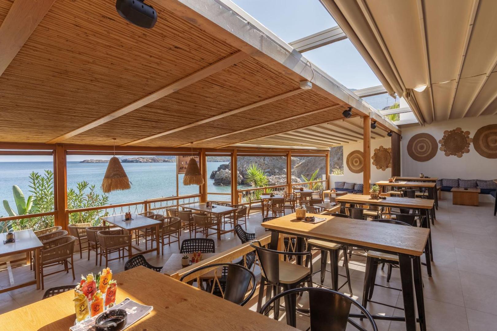 Bali Star Resort Hotel restorāna terase ar koka mēbelēm un skatu uz jūru — stilīgs interjers ar pītiem gaismekļiem