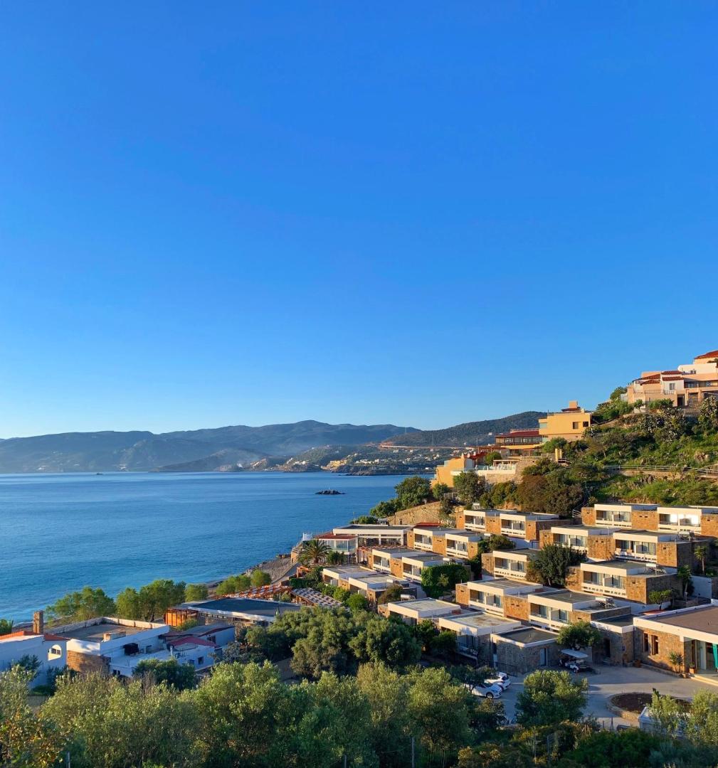 Ariadne Beach Hotel numuru korpusi kalna nogāzē pie jūras līča Malijā, Krētas salā, zaļumu ieskauti