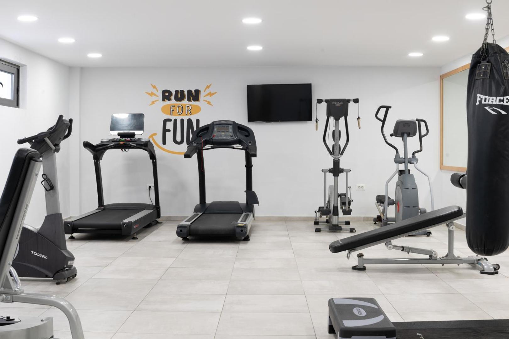 Tuvplāns Ariadne Beach Hotel trenažieru zālei ar skrejceļiem un motivējošu uzrakstu uz sienas Malijas kūrortviesnīcā