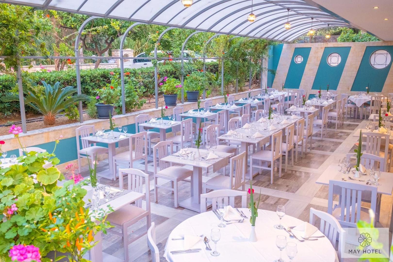May Beach Hotel restorāna iekštelpas ar balti klātiem galdiem un stiklotu jumtu — gaišs un elegants interjers