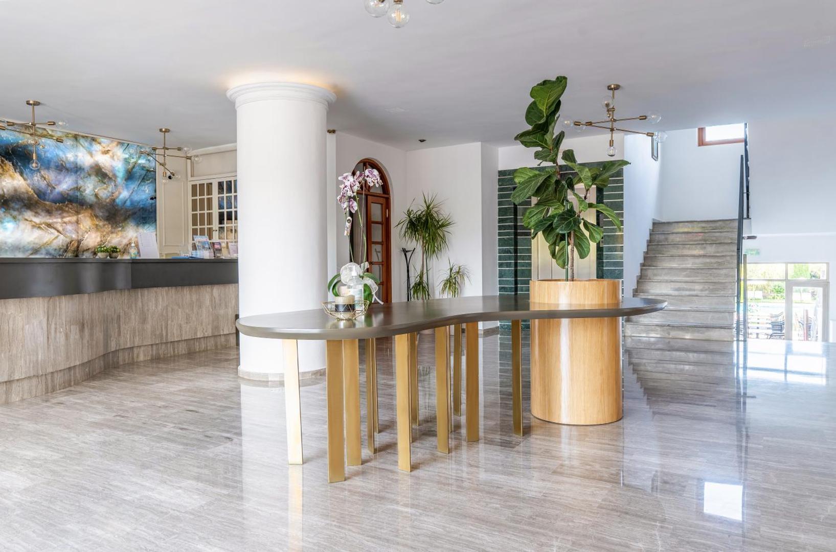 Plašs un gaišs May Hotel vestibils ar marmora grīdu, modernām mēbelēm un dekoratīviem augiem viesnīcas koplietošanas telpās