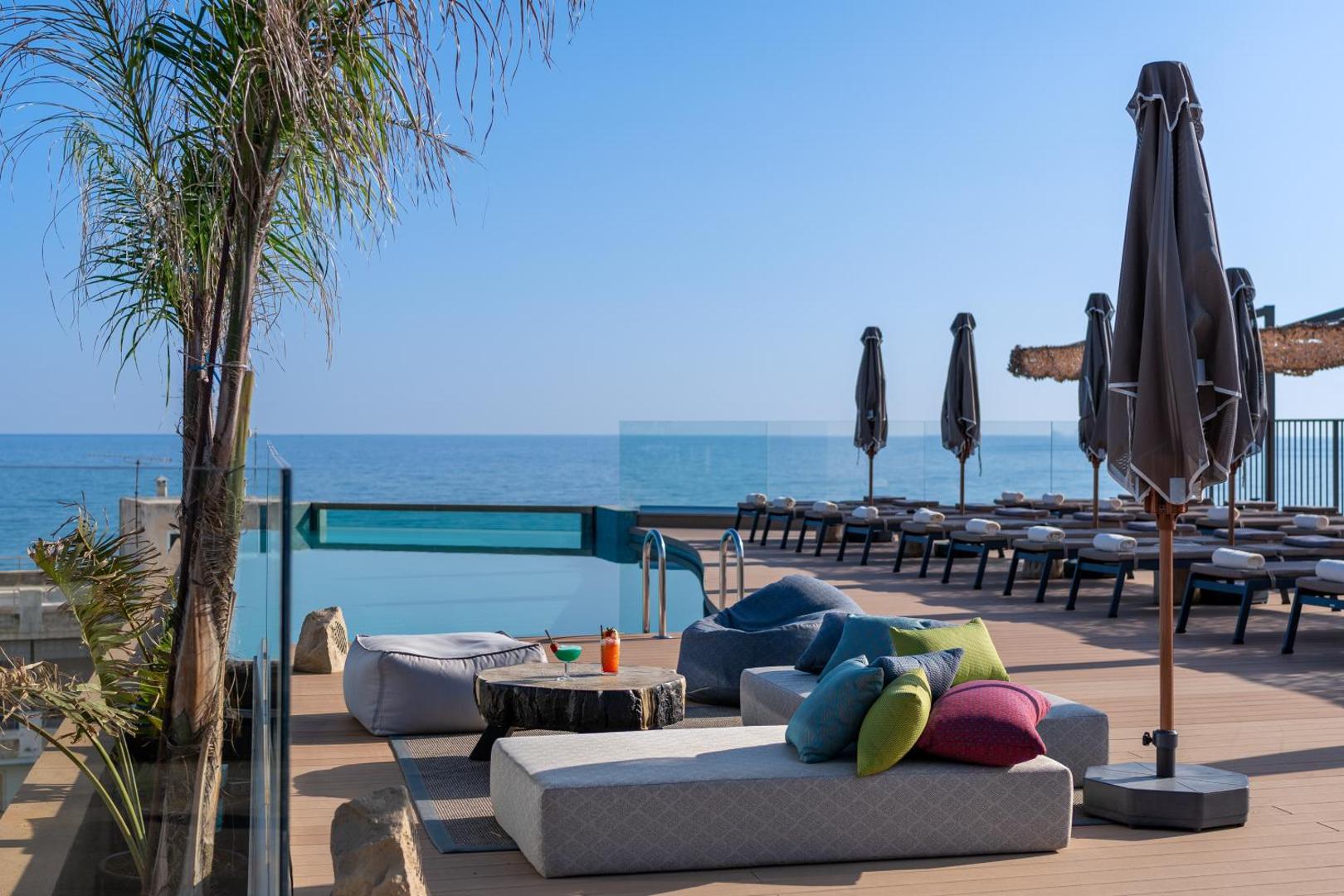 Minos Ambassador Suites & Spa atpūtas zona uz jumta ar mīkstajiem sēžammaisiem, kokteiļiem un skatu uz jūru Krētā