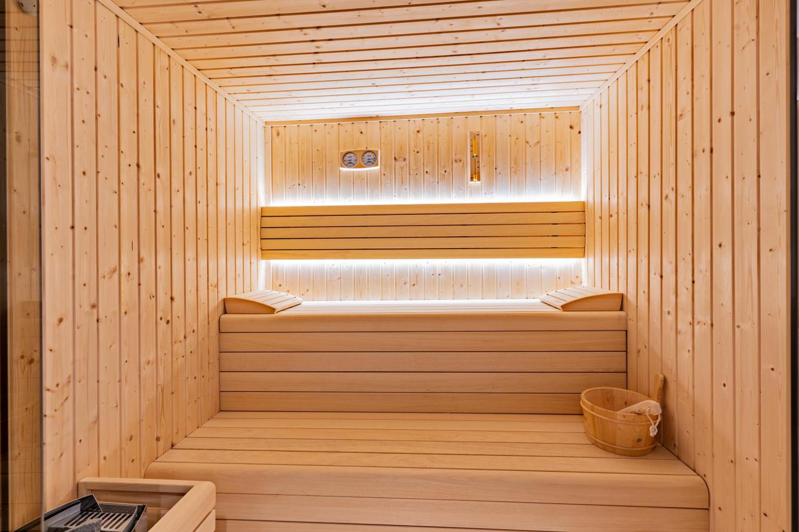 Minos Ambassador Suites & Spa viesnīcas moderna koka sauna ar apgaismojumu un tradicionālo pirts aprīkojumu relaksācijai