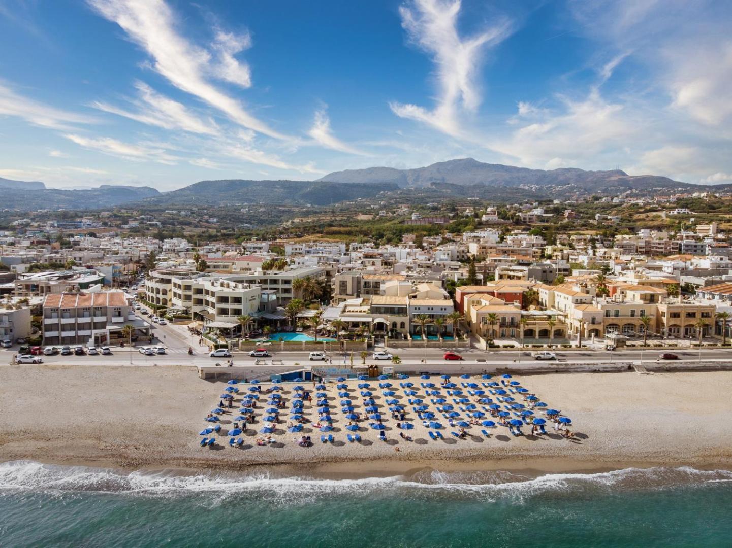 Sentido Aegean Pearl panorāmas skats uz viesnīcas kompleksu un plašo smilšu pludmali Retimno piekrastē, Krētā ar kalnu fonu