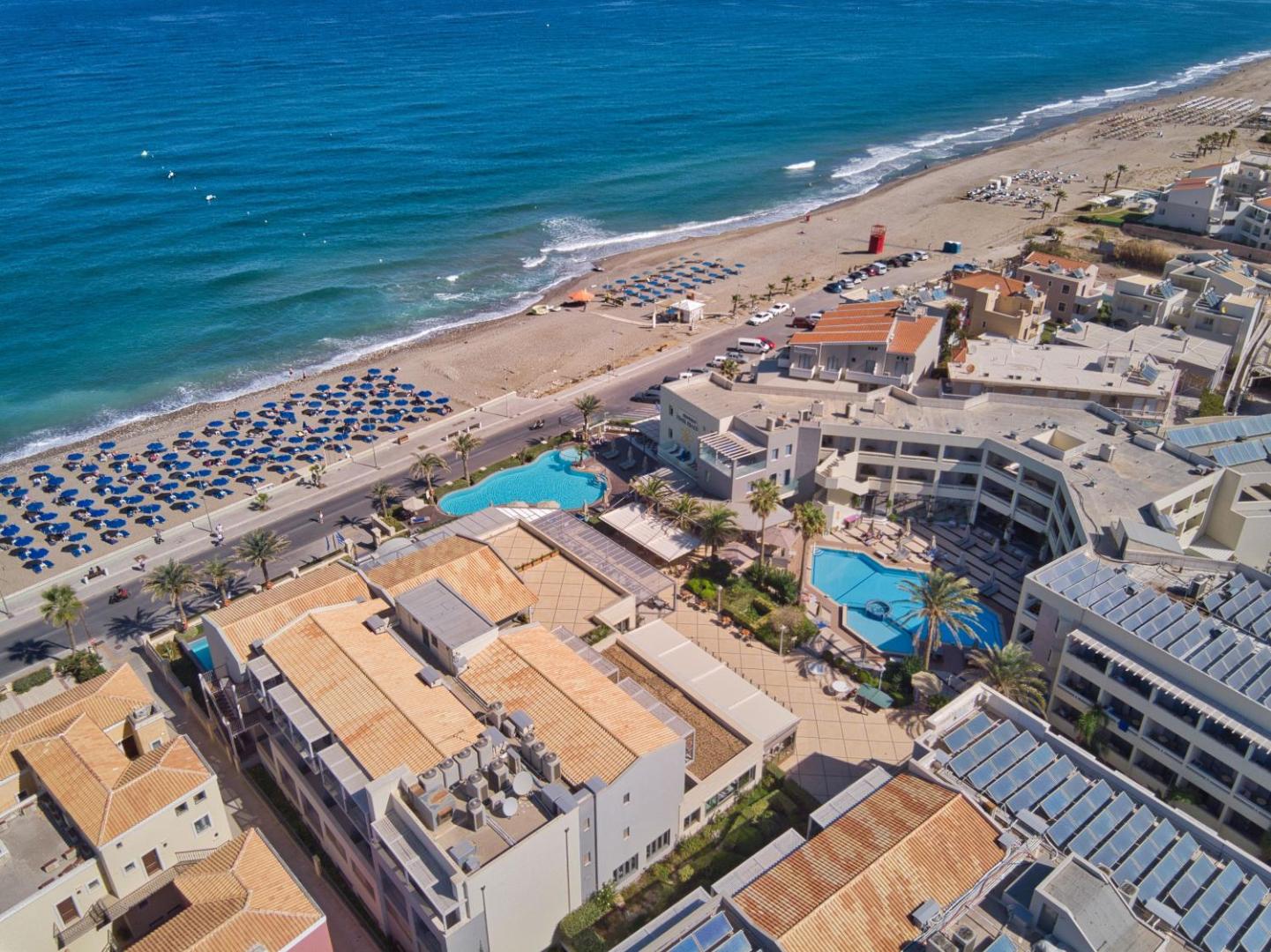 Sentido Aegean Pearl skats no augšas uz āra baseiniem, viesnīcas korpusiem un jūras krasta līniju saulainā dienā