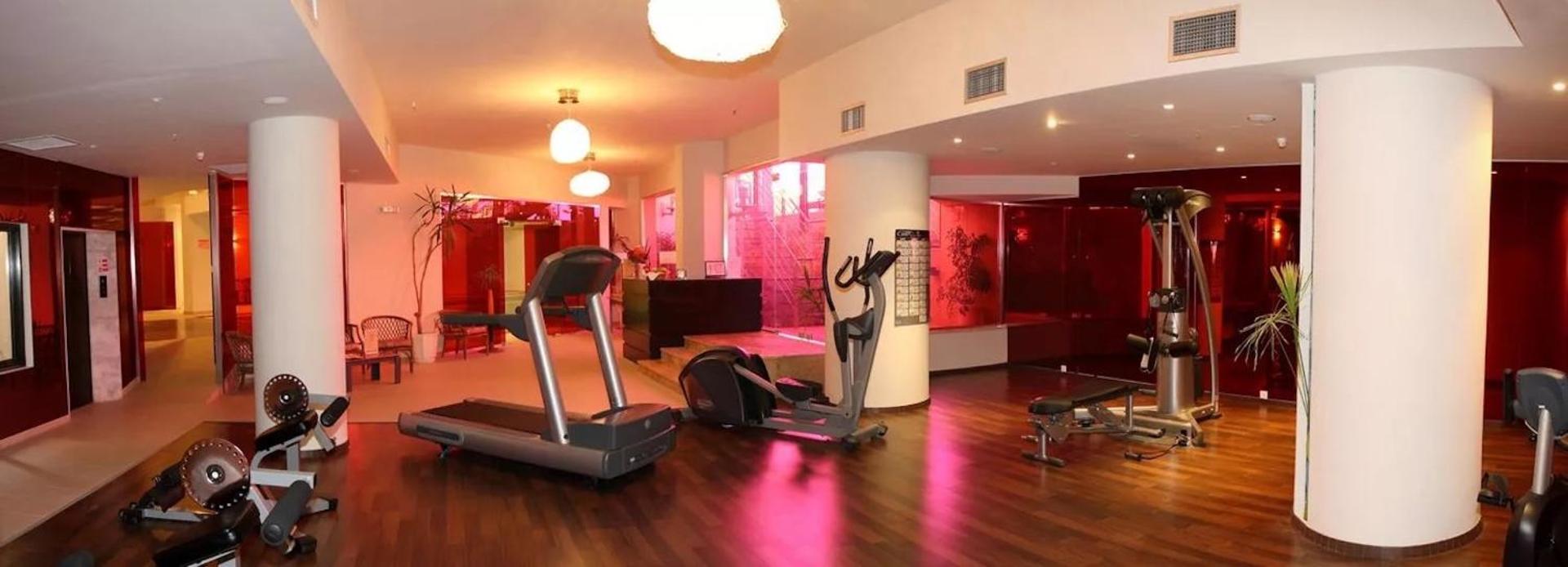 Aegean Pearl fitnesa centrs ar moderniem skrejceliņiem, trenažieriem un sarkanu apgaismojumu, nodrošinot vietu sportiskām aktivitātēm telpās