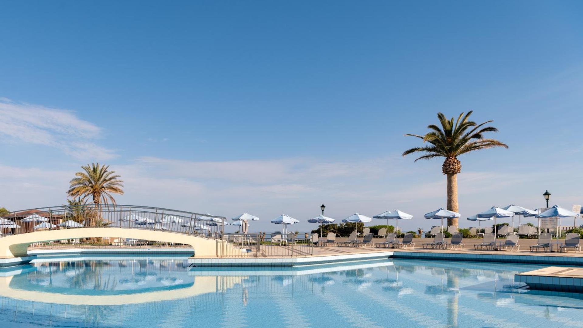 Creta Star Hotel plašais āra baseins dienas laikā ar tiltiņu, saulessargiem un skatu uz Vidusjūru Krētā