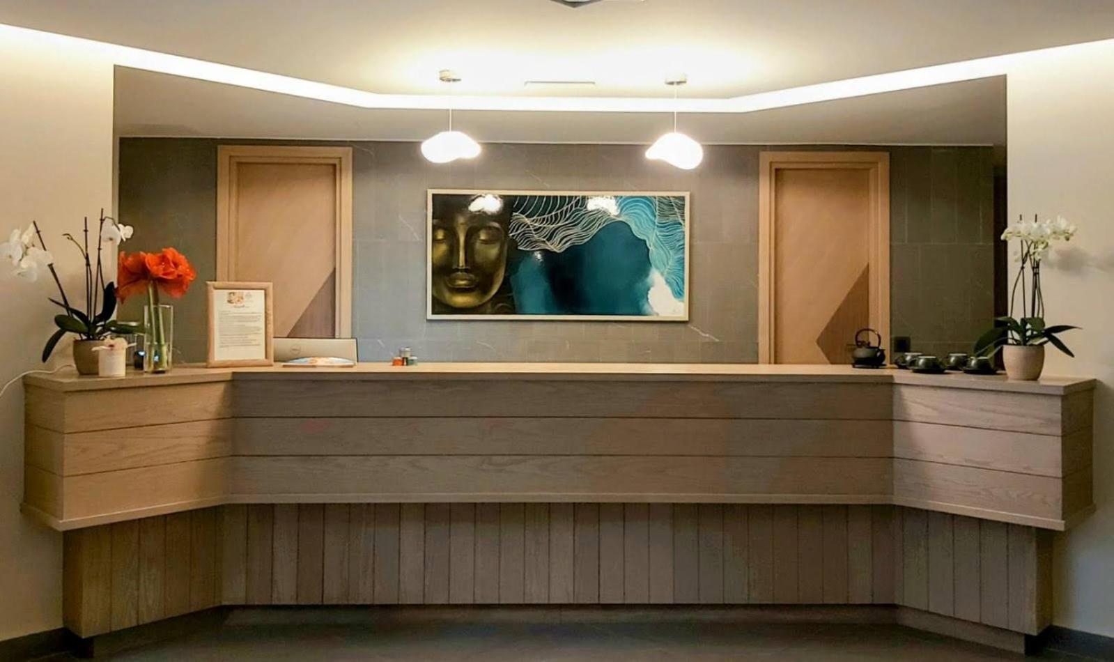 Amira Luxury Resort recepcijas zona ar koka apdari un mākslas darbu pie sienas — mierīga un eleganta viesu uzņemšanas telpa