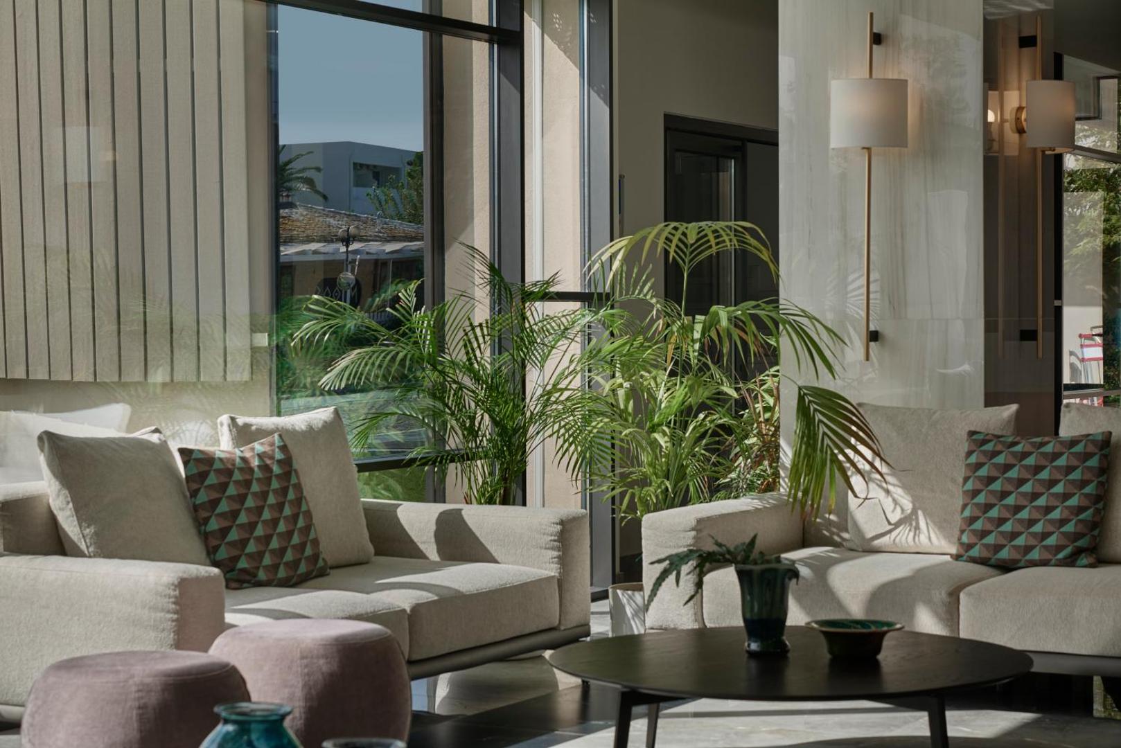 Amira Luxury Resort atpūtas zona ar mīkstajiem dīvāniem, dekoratīviem spilveniem un lieliem logiem uz dārzu