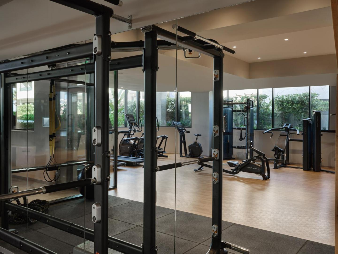 Amira Luxury Resort modernais fitness centrs ar Matrix trenažieriem un lieliem spoguļiem — gaiša telpa sportiskām aktivitātēm