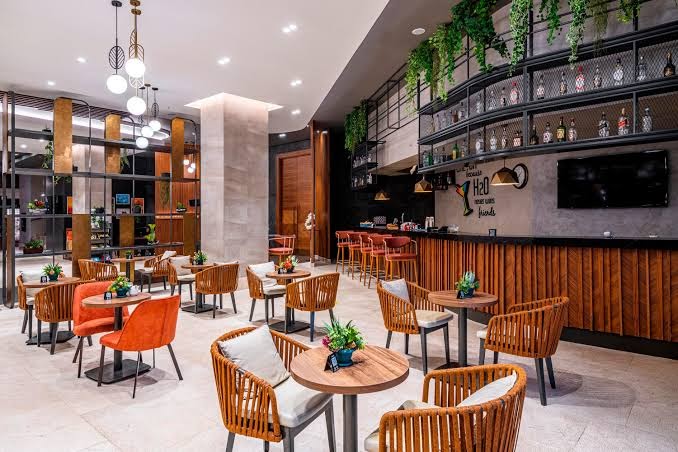 Kirman Calyptus Resort & SPA bāra zona ar augstajiem krēsliem, dekoratīviem augiem un mājīgu apgaismojumu atpūtas telpā