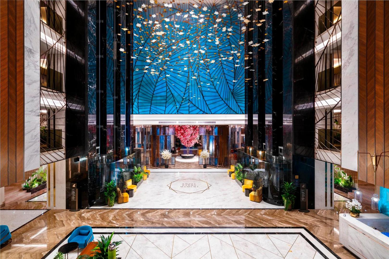 Kirman Calyptus Resort & SPA iespaidīgais vestibils ar augstiem griestiem, modernu apgaismojumu un marmora grīdām — luksusa klases interjers.