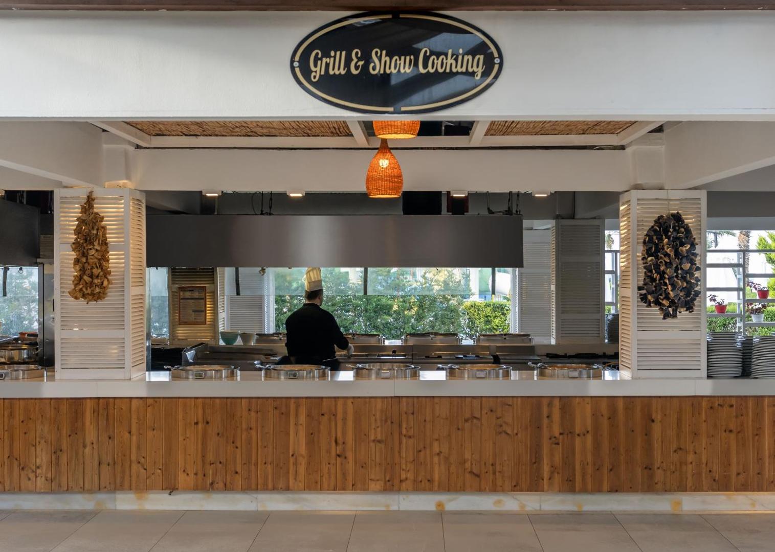 Kaya Side viesnīcas Grill & Show Cooking stacija ar atvērto virtuvi, kur pavāri gatavo ēdienus viesu acu priekšā.