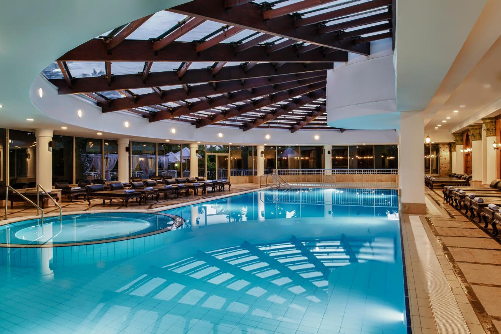 Delphin Diva iekštelpu baseins ar apsildi, stikla jumtu un atpūtas krēsliem spa zonā Antaljas viesnīcā