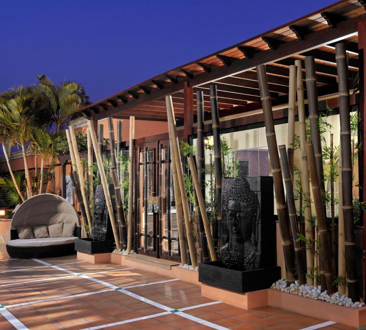 Green Garden Eco Resort viesnīcas eksterjers vakarā ar bambusa elementiem un dekoratīvām Budas strūklakām Tenerifē pie baseina zonas