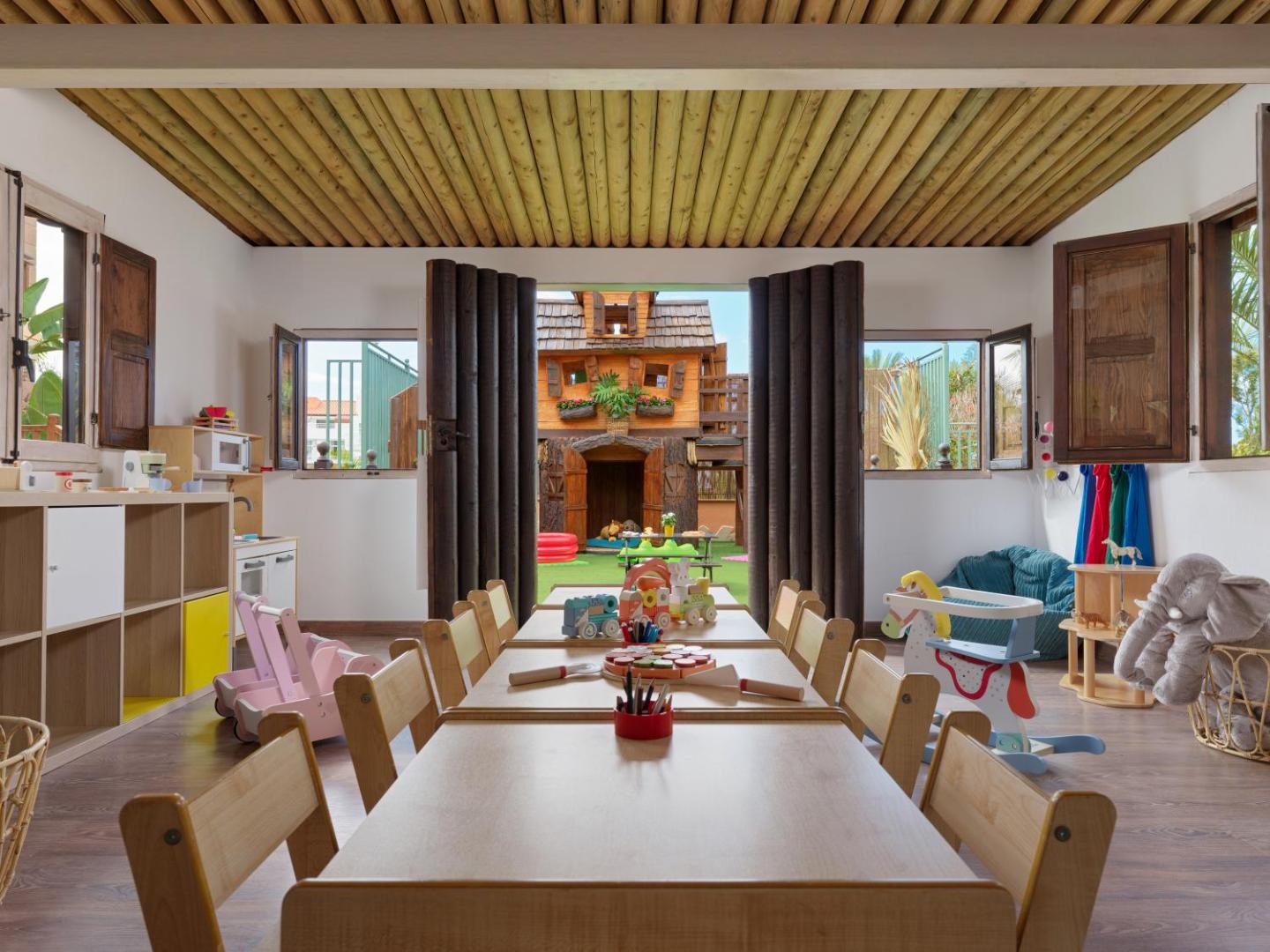 Green Garden Eco Resort bērnu kluba iekštelpas ar rotaļlietām, galdiem radošām nodarbībām un skatu uz āra rotaļu zonu