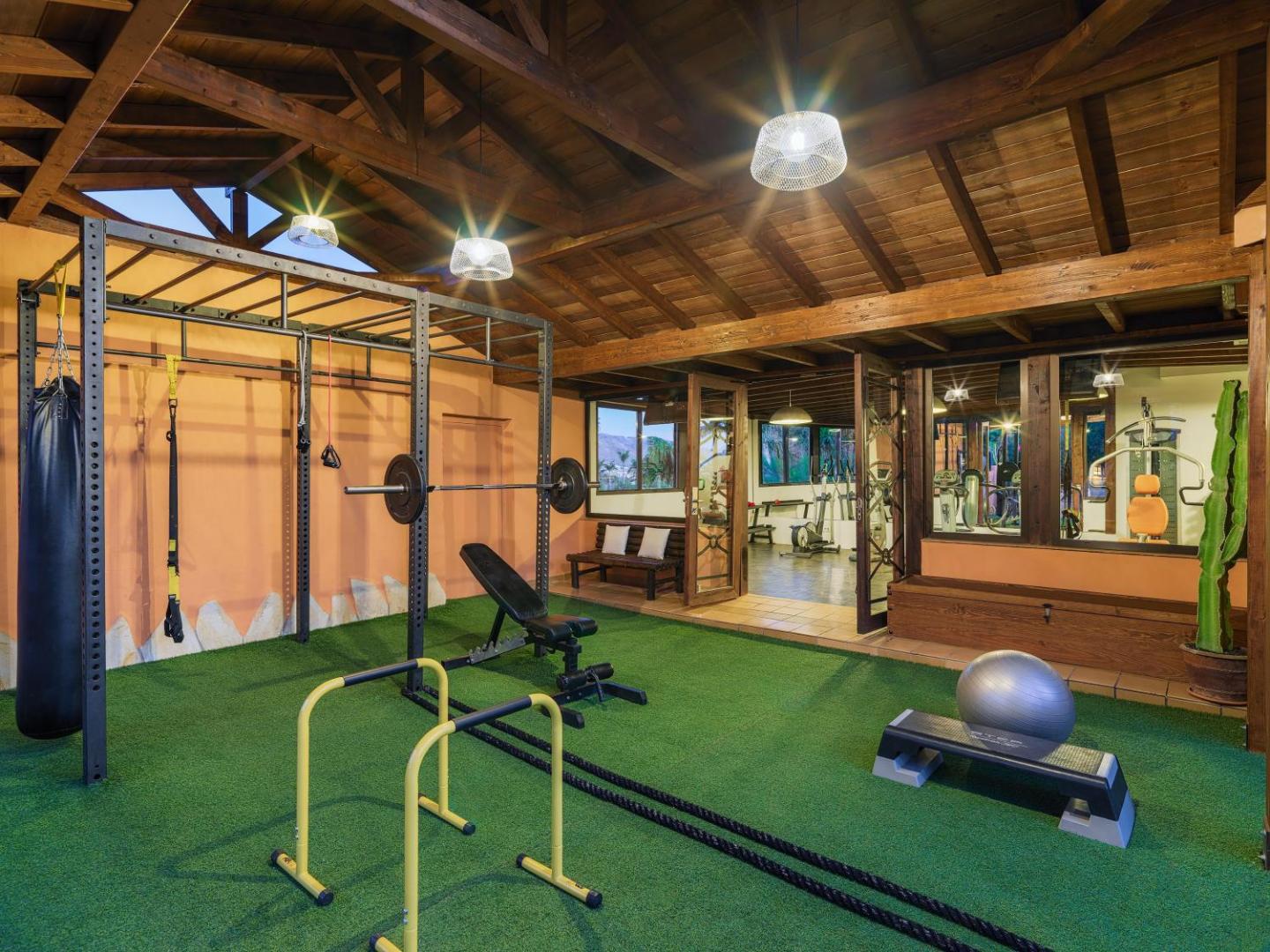 Green Garden Eco Resort modernā fitness zona ar koka griestiem, mākslīgo zālienu un profesionālu svaru celšanas un krosa aprīkojumu