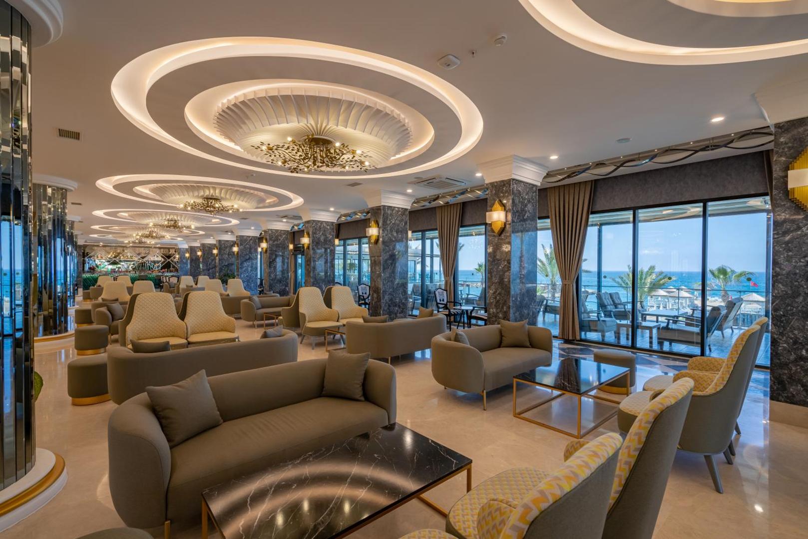 Aria Resort & Spa Hotel lobby bāra atpūtas zona ar mīkstajiem dīvāniem, lieliem logiem un skatu uz jūru Alānijā