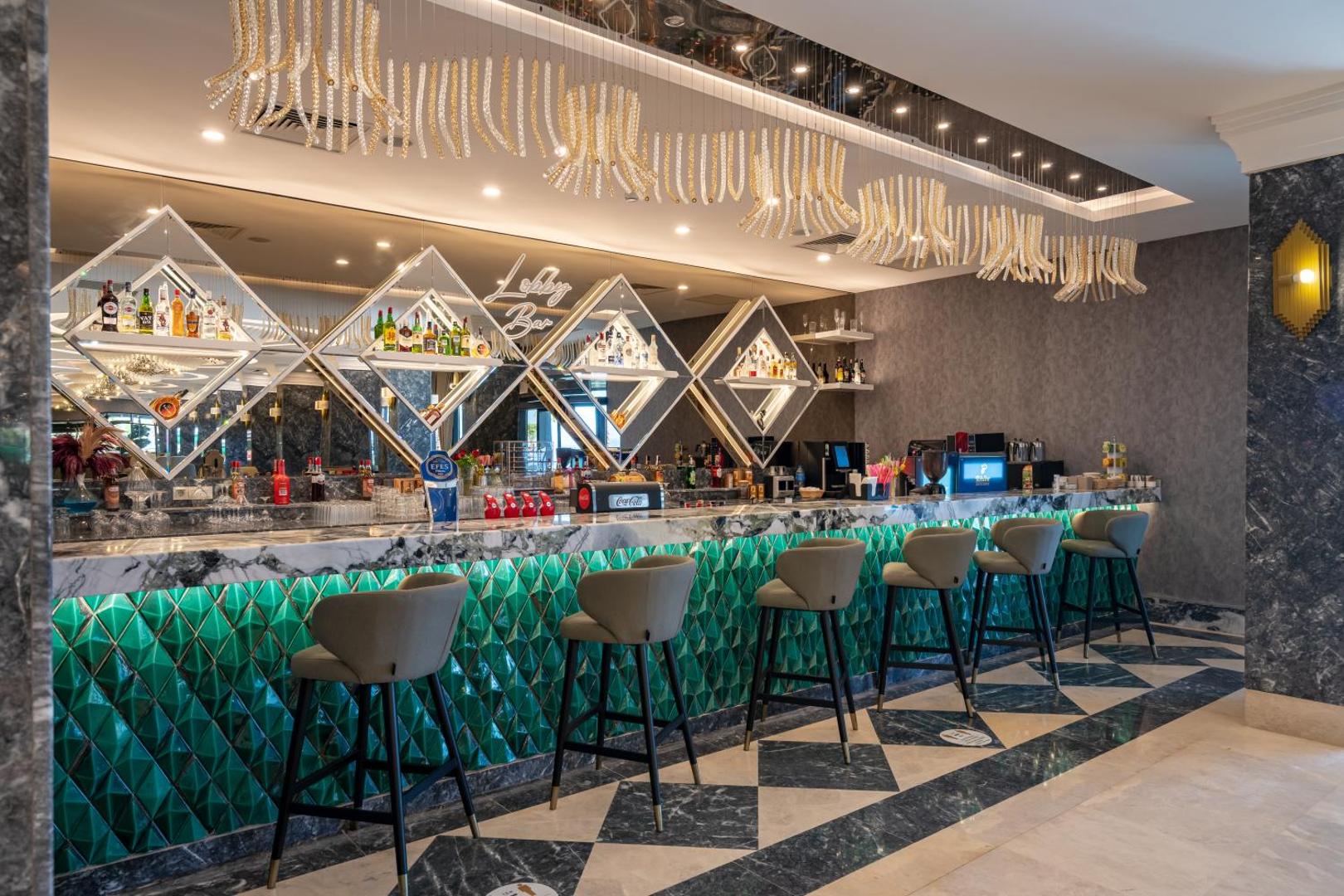 Aria Resort & Spa Hotel lobby bārs ar modernu leti, smaragdzaļu apdari un plašu dzērienu izvēli Alānijas kūrortā