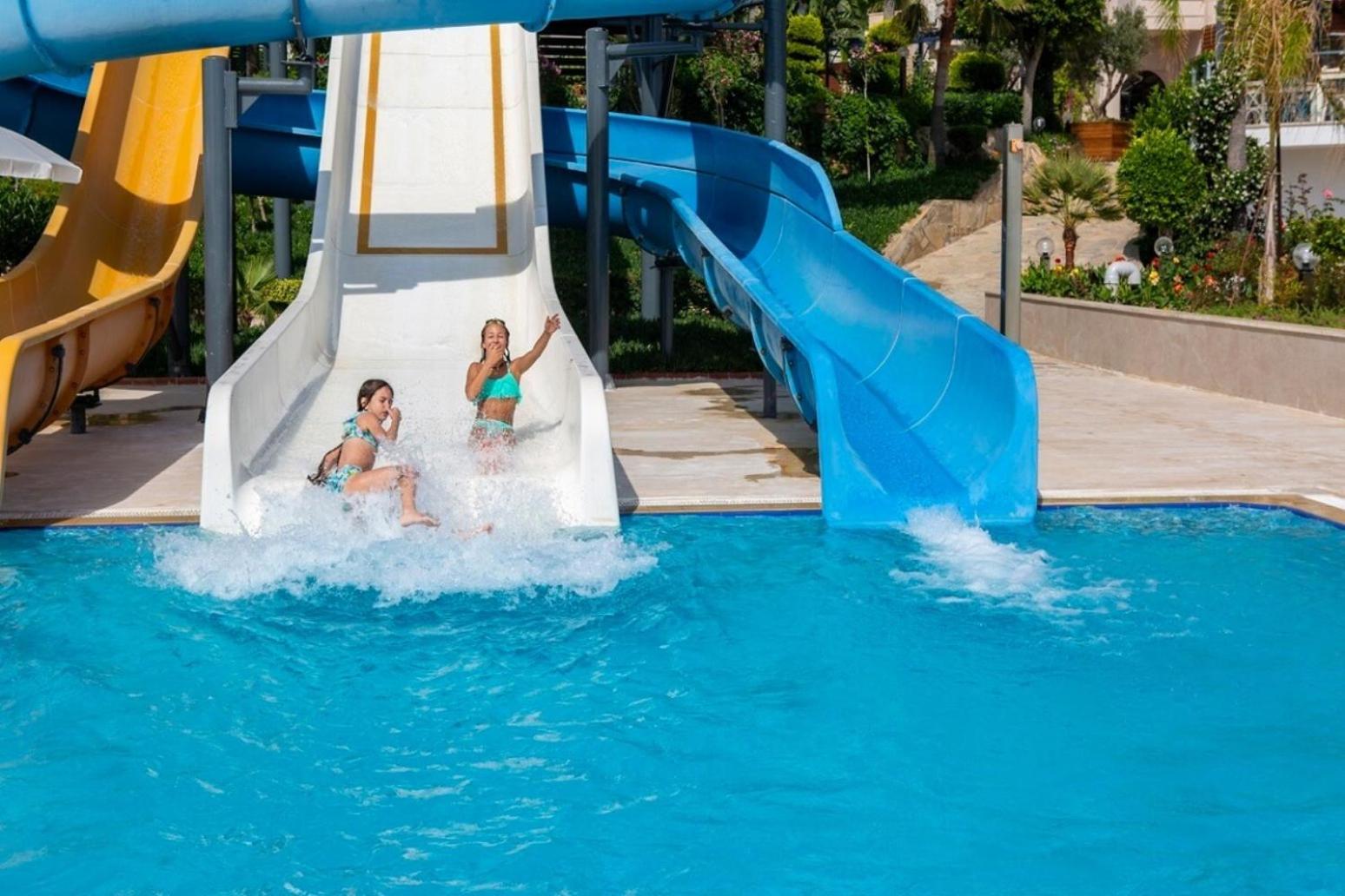 Bērni šļūc pa krāsainiem ūdens slidkalniņiem Aria Resort & Spa viesnīcas akvaparka zonā Alanjā