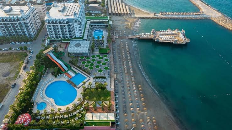 Aria Resort & Spa Hotel skats no augšas uz baseinu zonu, ūdens slidkalniņiem un privāto pludmali ar koka piestātni