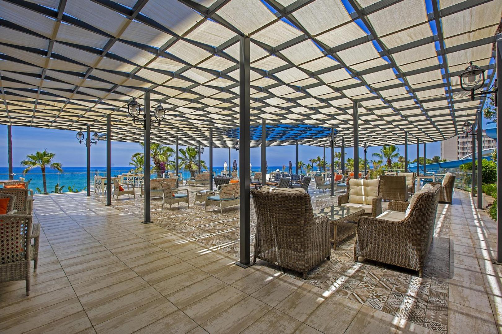 Aria Resort & Spa Hotel āra terase ar pītiem atpūtas krēsliem zem nojumes un skatu uz Vidusjūru Alānijā, Turcijā