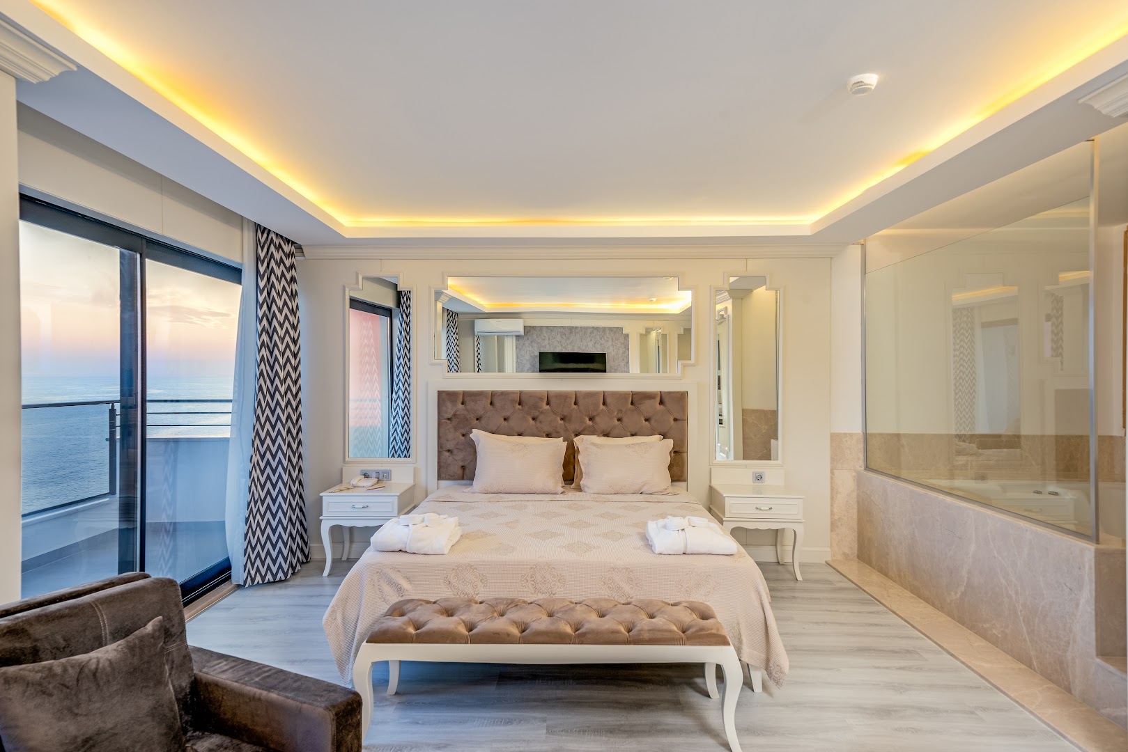 Aria Resort & Spa viesnīcas numura interjers ar lielu gultu, spoguļiem un stiklotu vannasistabas sienu Alanjas piekrastē