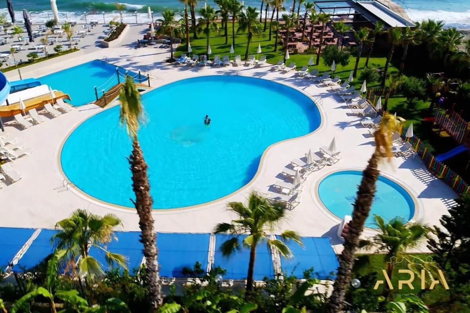 Aria Resort & Spa āra baseinu zona no augšas ar bērnu baseinu, palmām un sauļošanās krēsliem pie jūras