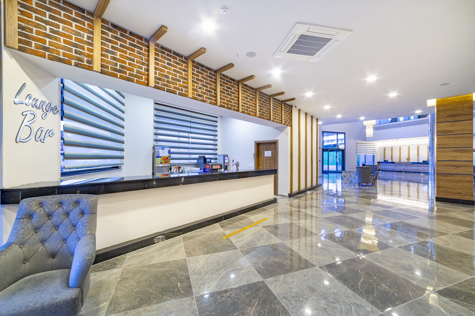 Lonicera Premium viesnīcas Lounge Bar vestibils ar marmora grīdu, modernu leti un atpūtas krēsliem Alanjas reģionā, Turcijā