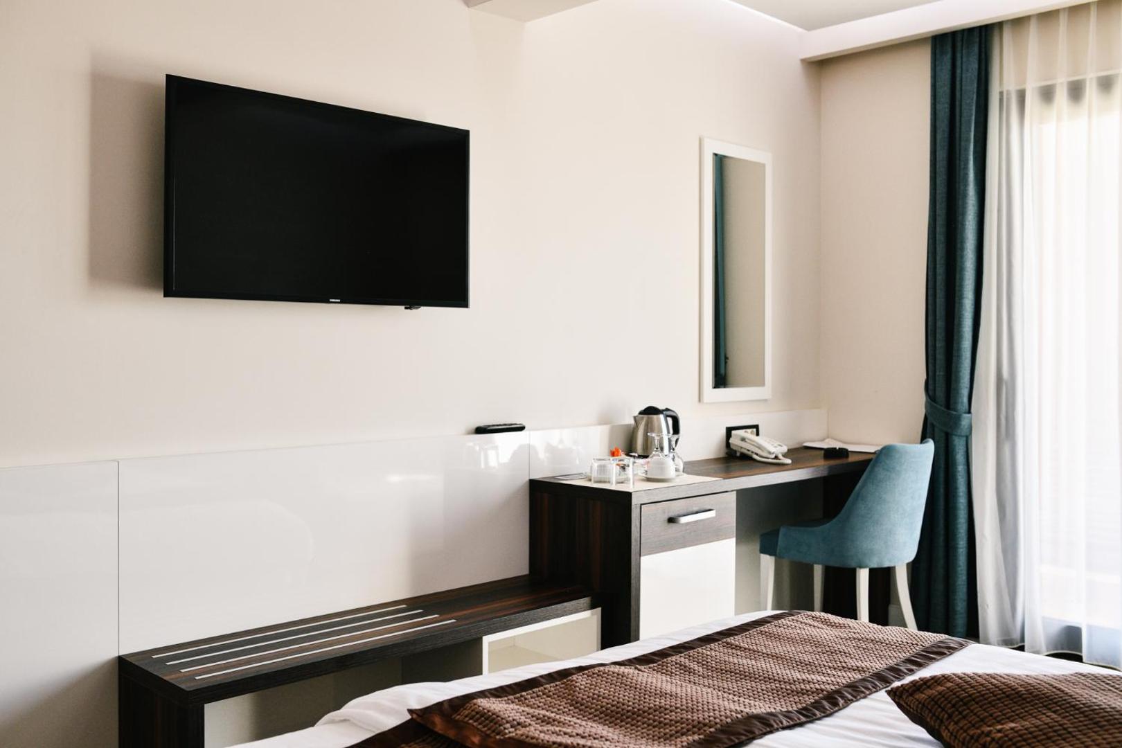 ACD Wellness & Spa numura darba galds ar tējkannu un spoguli, blakus lielam logam ar aizkariem, nodrošinot komfortu viesiem