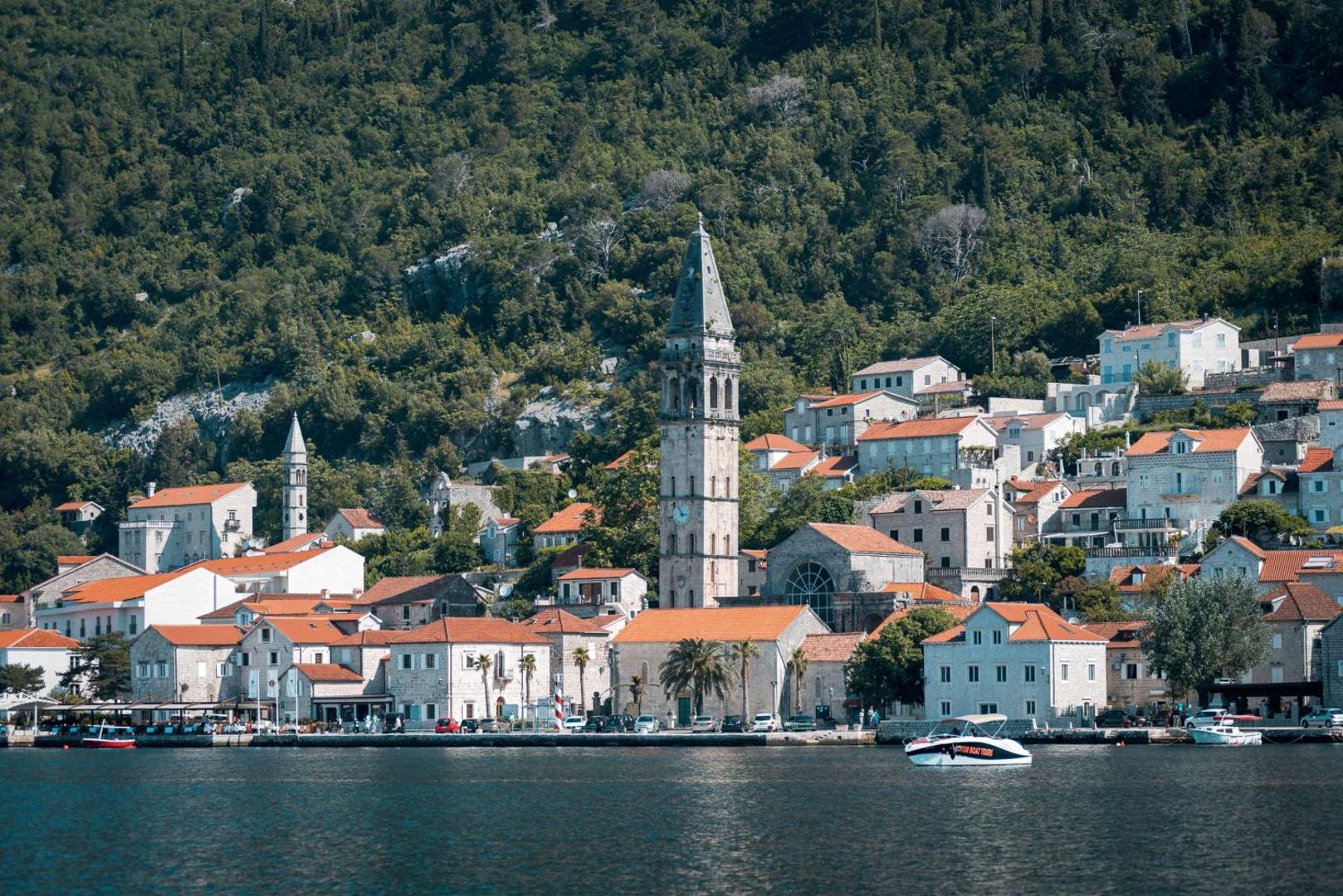 Skats no jūras uz Perastas pilsētiņu netālu no Hyatt Regency Kotor Bay Resort — vēsturiska arhitektūra, baznīcas tornis un kalni