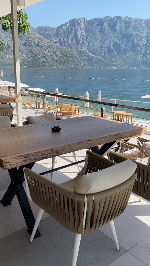 Viesnīcas Hyatt Regency Kotor Bay Resort āra restorāna terase ar koka galdiem un moderniem krēsliem pie pašas jūras krasta