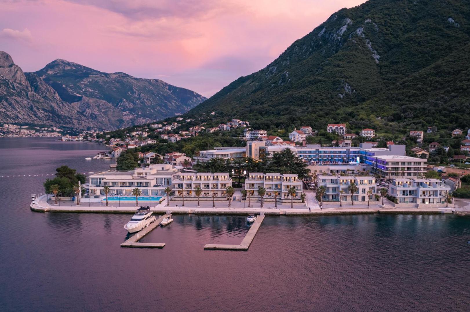 Hyatt Regency Kotor Bay Resort skats no putna lidojuma saulrietā — moderna viesnīcas arhitektūra pie līča krasta Melnkalnē
