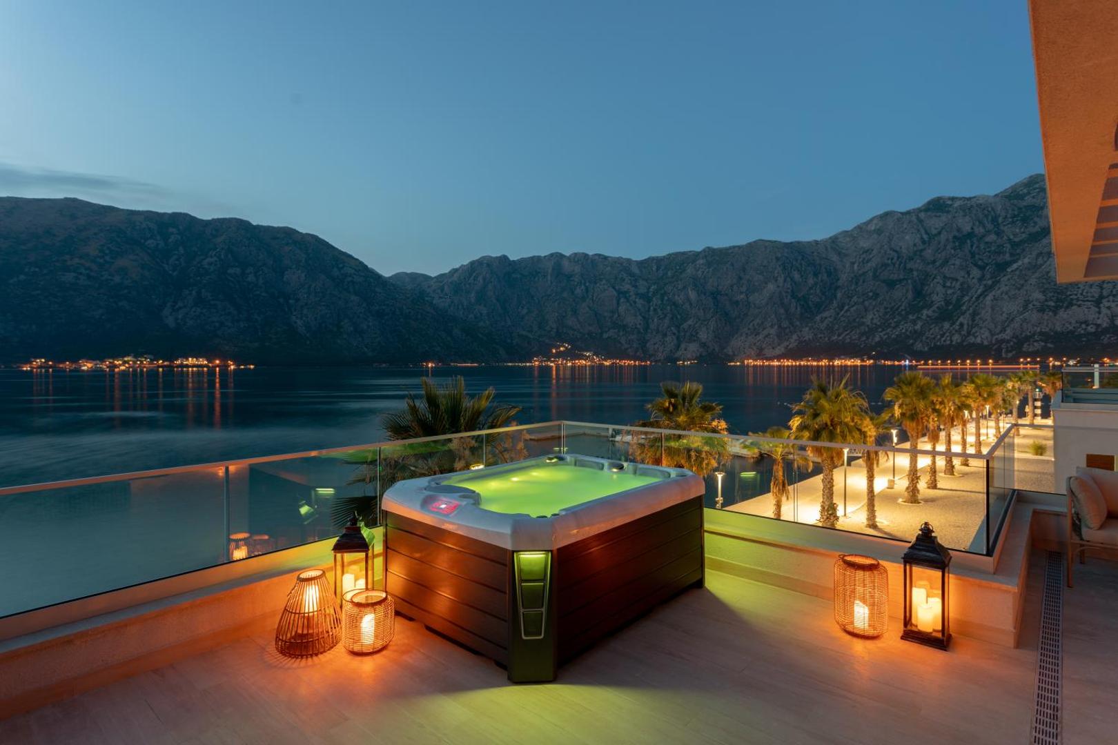 Hyatt Regency Kotor Bay Resort terase vakarā ar džakuzi un skatu uz naksnīgo Kotoras līci un kalniem