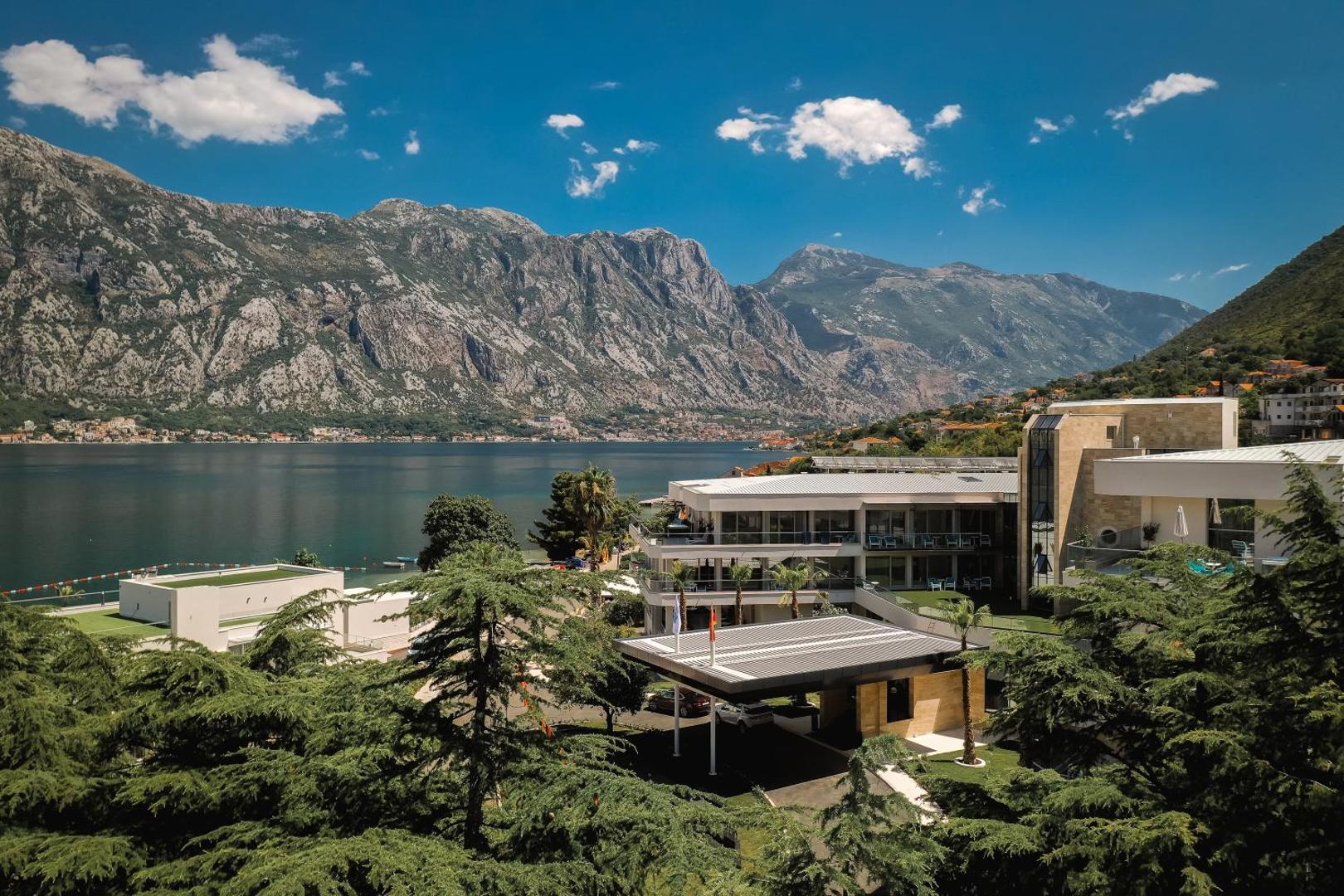 Hyatt Regency Kotor Bay Resort ēkas un koptā teritorija ar skatu uz Kotora līča ūdeņiem un akmeņainajām virsotnēm