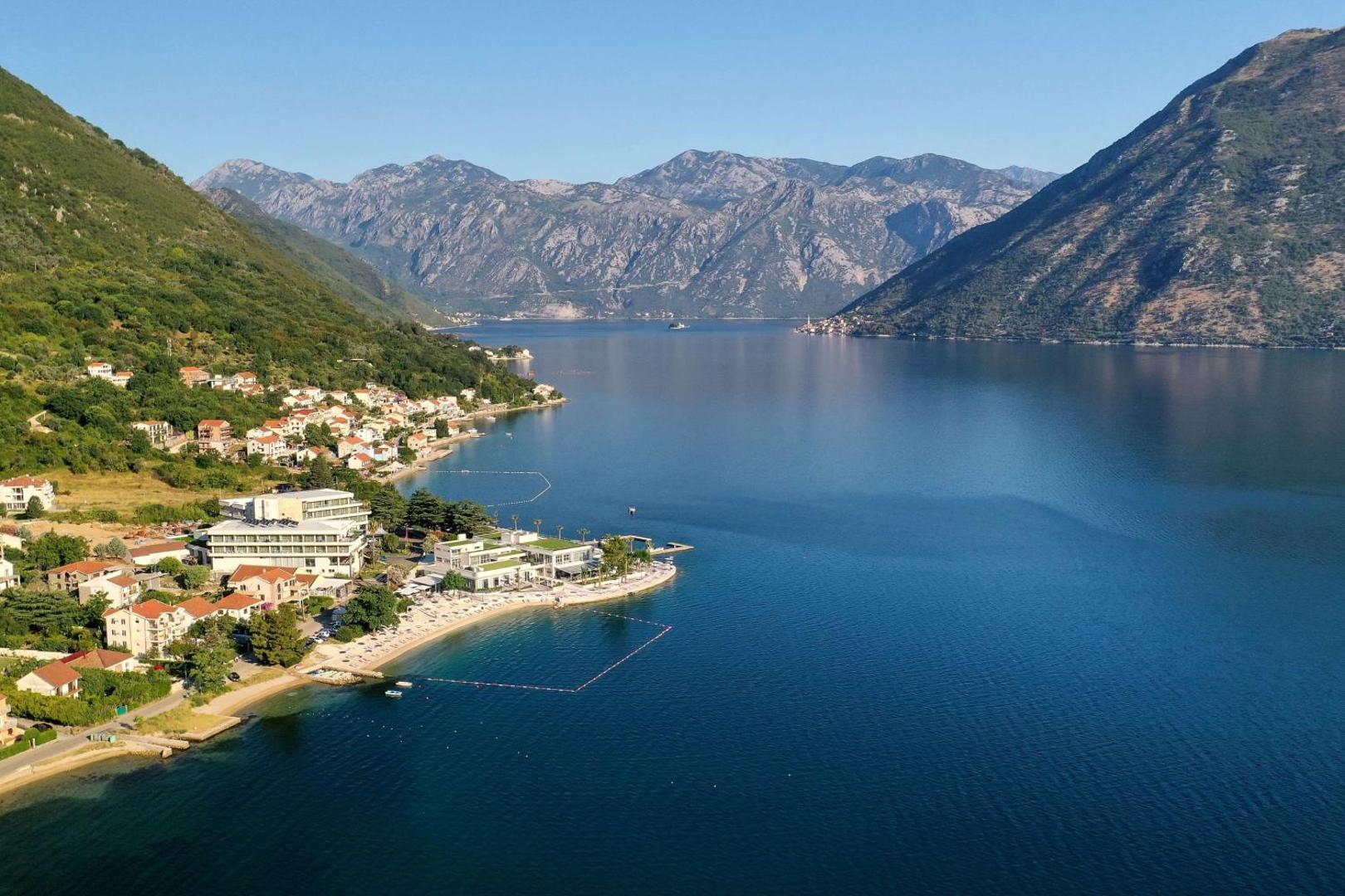 Panorāmas skats uz Hyatt Regency Kotor Bay Resort un zilo Adrijas jūras līci Melnkalnes kalnu ielokā saulainā dienā