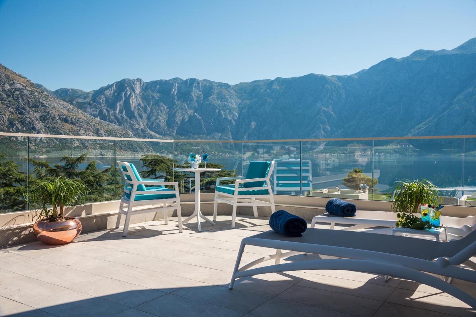 Hyatt Regency Kotor Bay Resort terases mēbeles un sauļošanās krēsli ar skatu uz kalnu grēdu un jūru