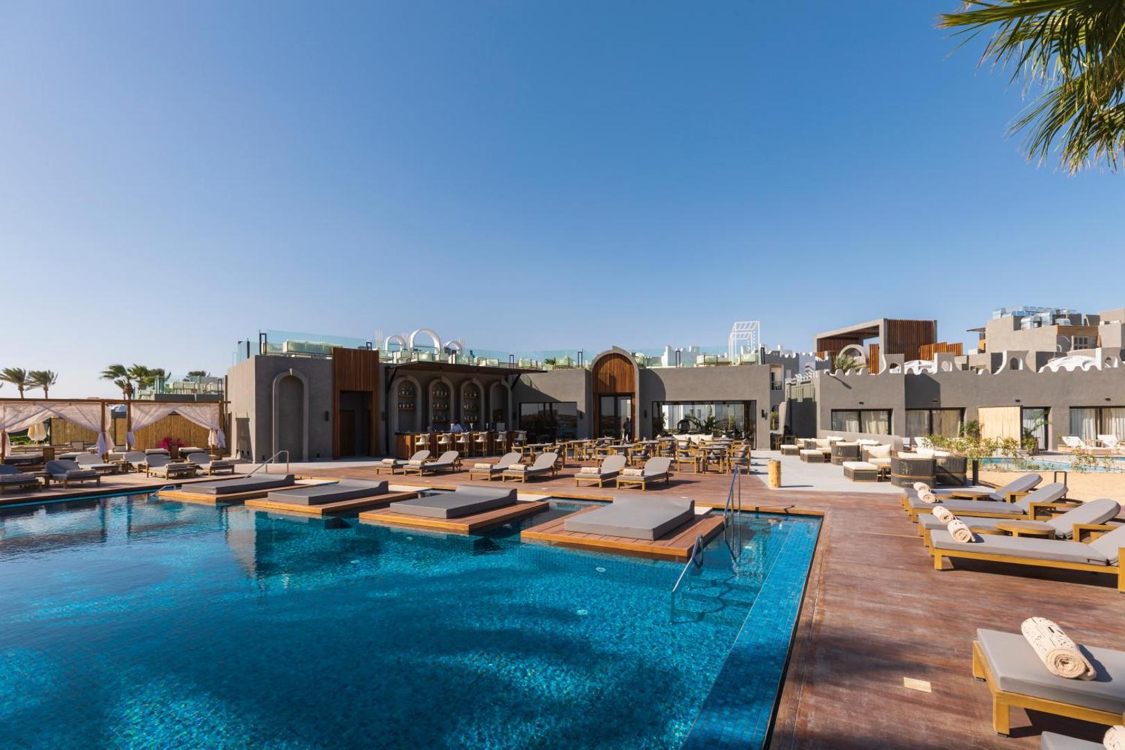 Sunrise Tucana Resort āra baseins ar sauļošanās platformām ūdenī, blakus esošu bāru un terasi Makadi Bay kūrortā.