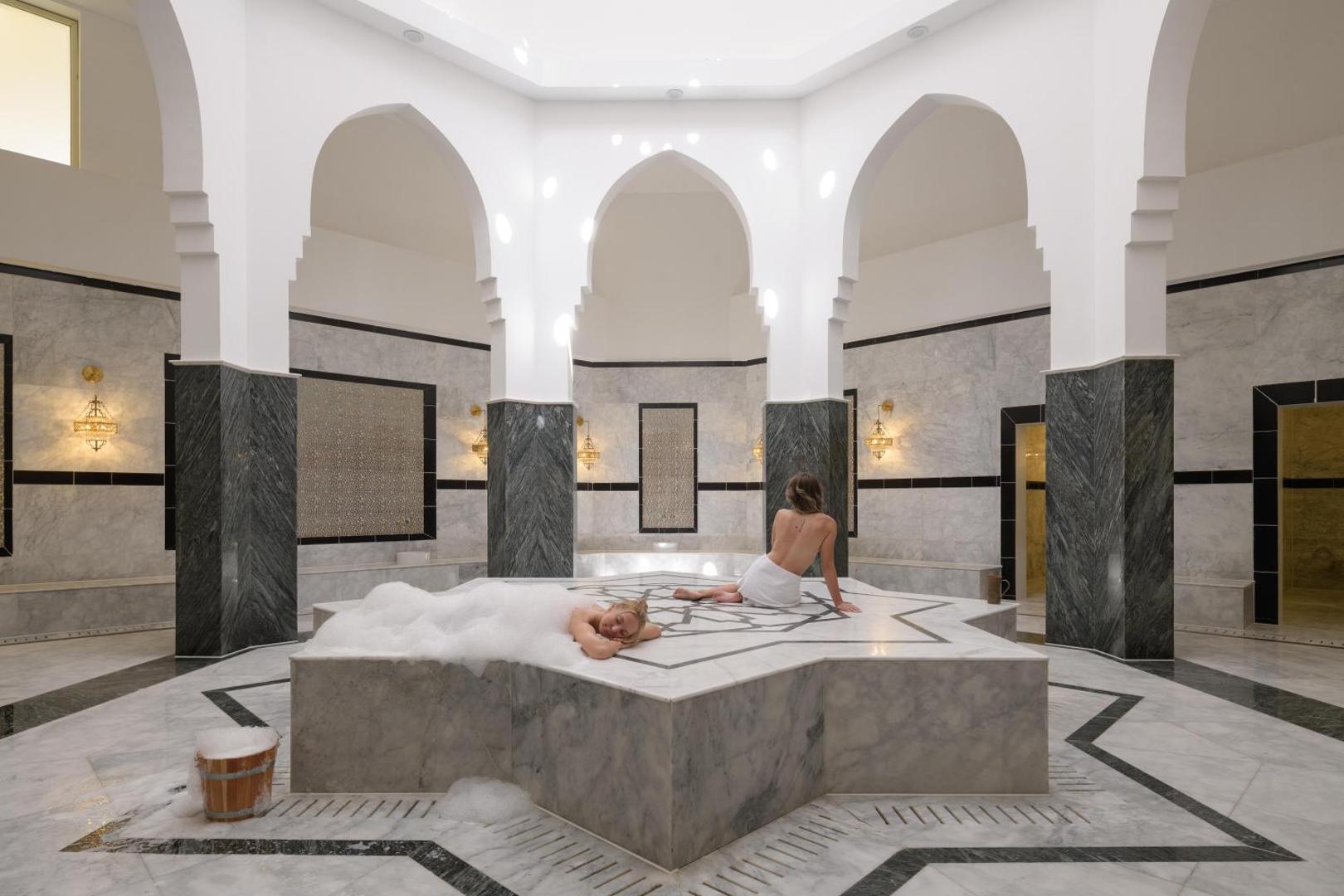 Tradicionāls turku hamams Xanadu Makadi Bay viesnīcā ar marmora apdari, arkām un apsildāmu akmens platformu relaksācijai.