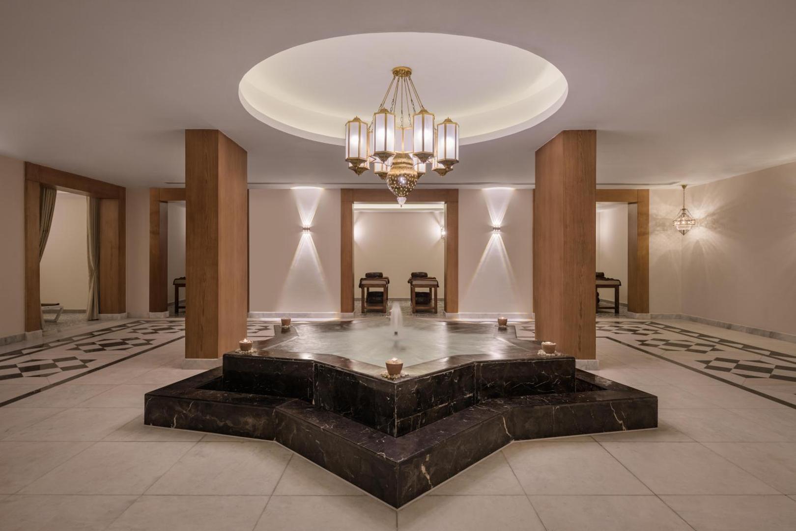 Xanadu Makadi Bay spa zonas interjers ar centrālo strūklaku zvaigznes formā, masāžas galdiem fonā un austrumniecisku lustru.