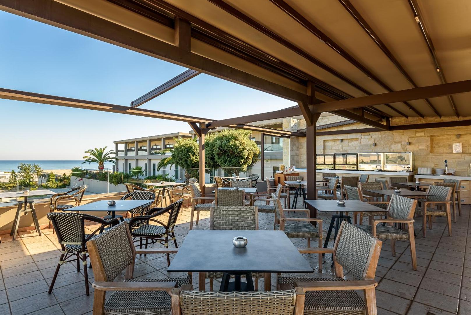Solimar Aquamarine Resort restorāna āra terase ar modernām mēbelēm zem nojumes un skatu uz jūru un viesnīcas dārzu