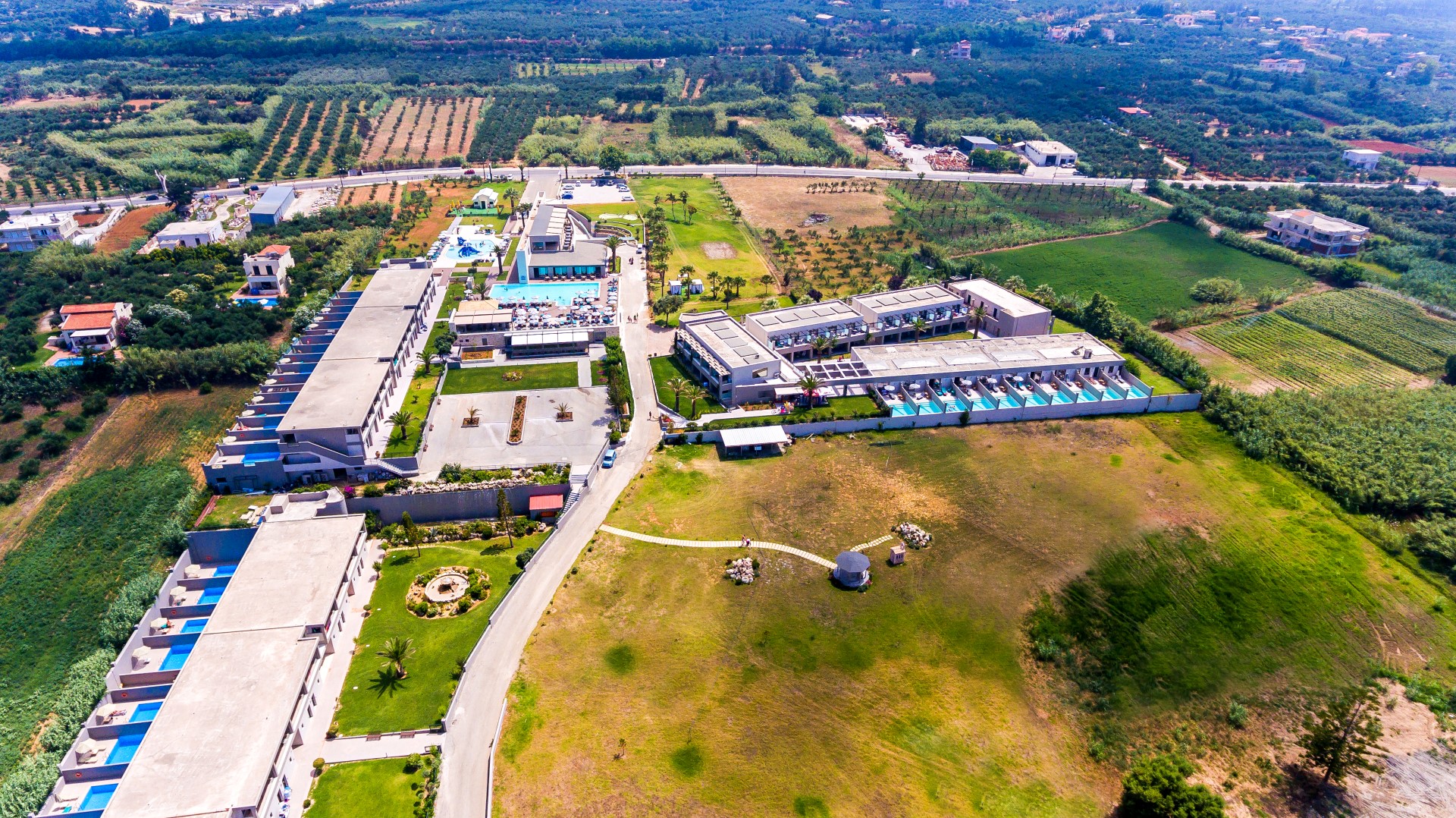 Solimar Aquamarine Resort panorāmas skats no augšas Gerani rajonā, Krētā — plaša teritorija ar baseiniem, dārzu un modernām ēkām pie jūras