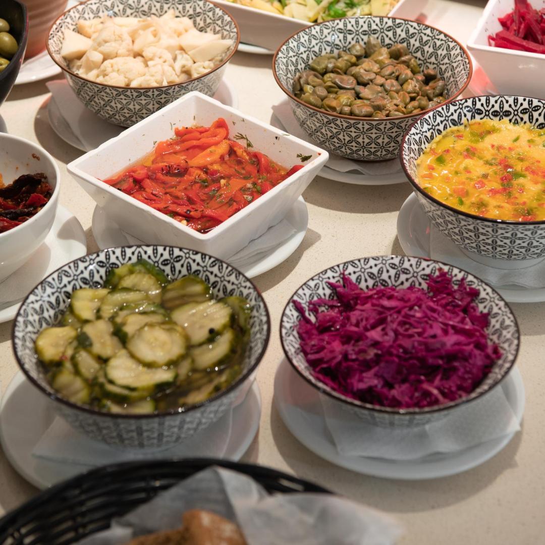 BIO Suites Hotel & Spa restorāna uzkodu izvēle — dažādi marinēti dārzeņi un tradicionālās mērces dekoratīvos traukos