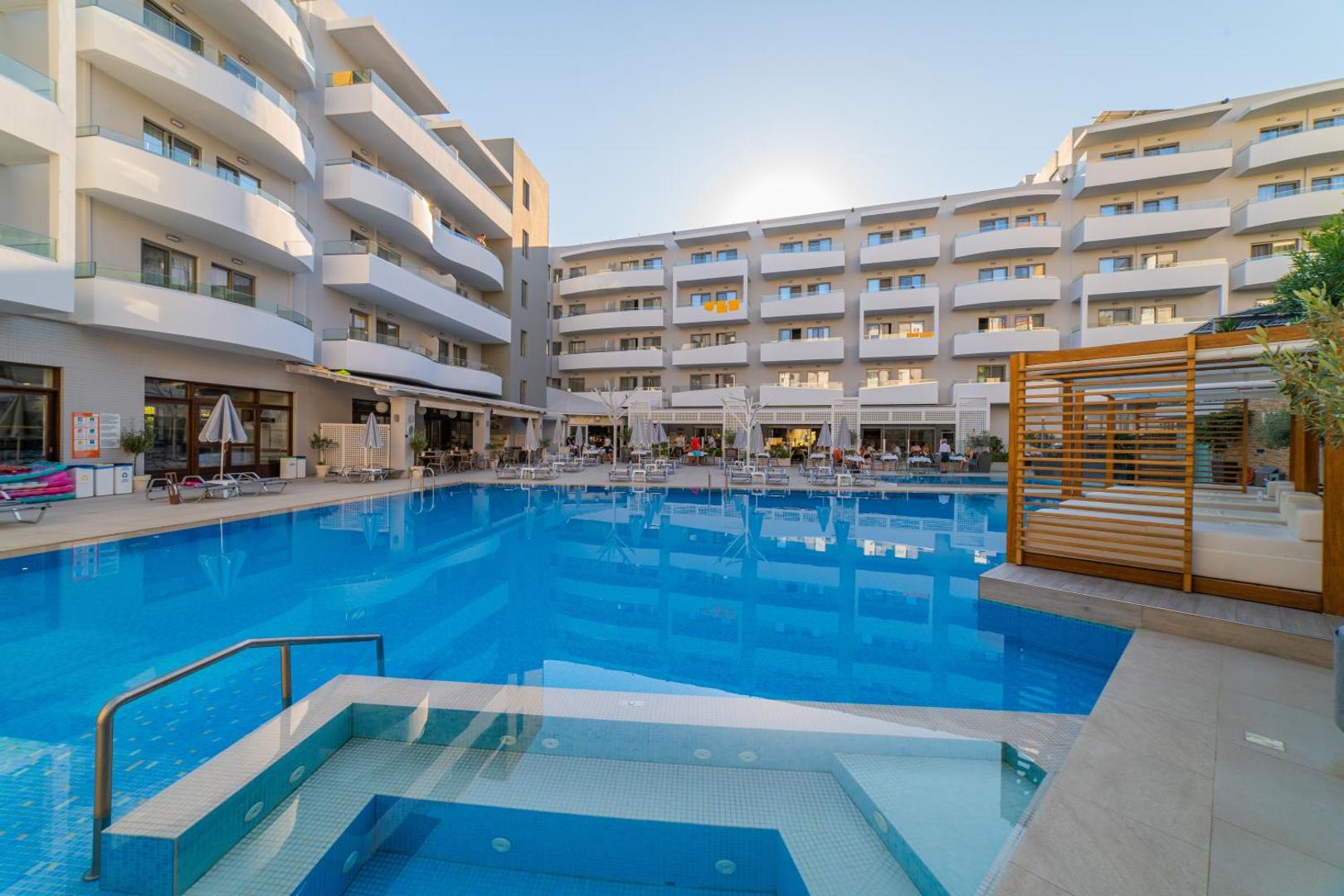 BIO Suites Hotel & Spa āra baseins Retimno pilsētā Krētā — skats uz viesnīcas korpusu ar balkoniem un saulainu atpūtas zonu