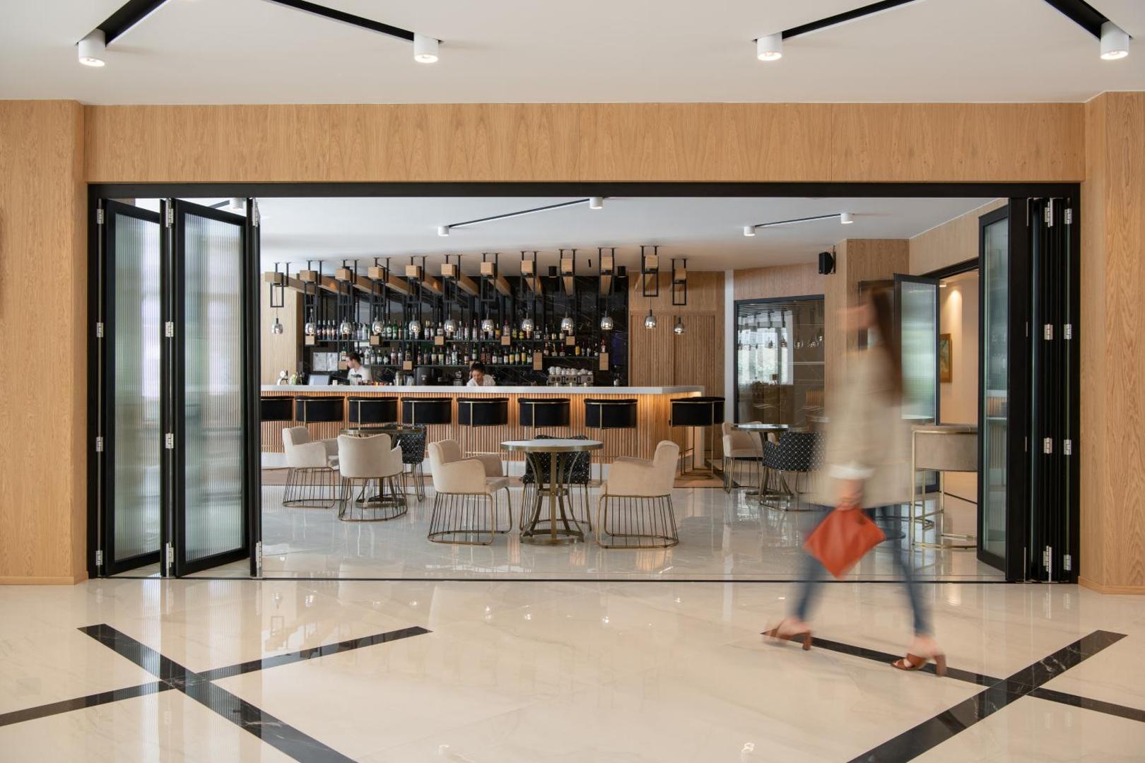 BIO Suites Hotel & Spa modernais vestibila bārs Retimno, Krētā — elegants interjers ar gaišām mēbelēm un plašu dzērienu izvēli