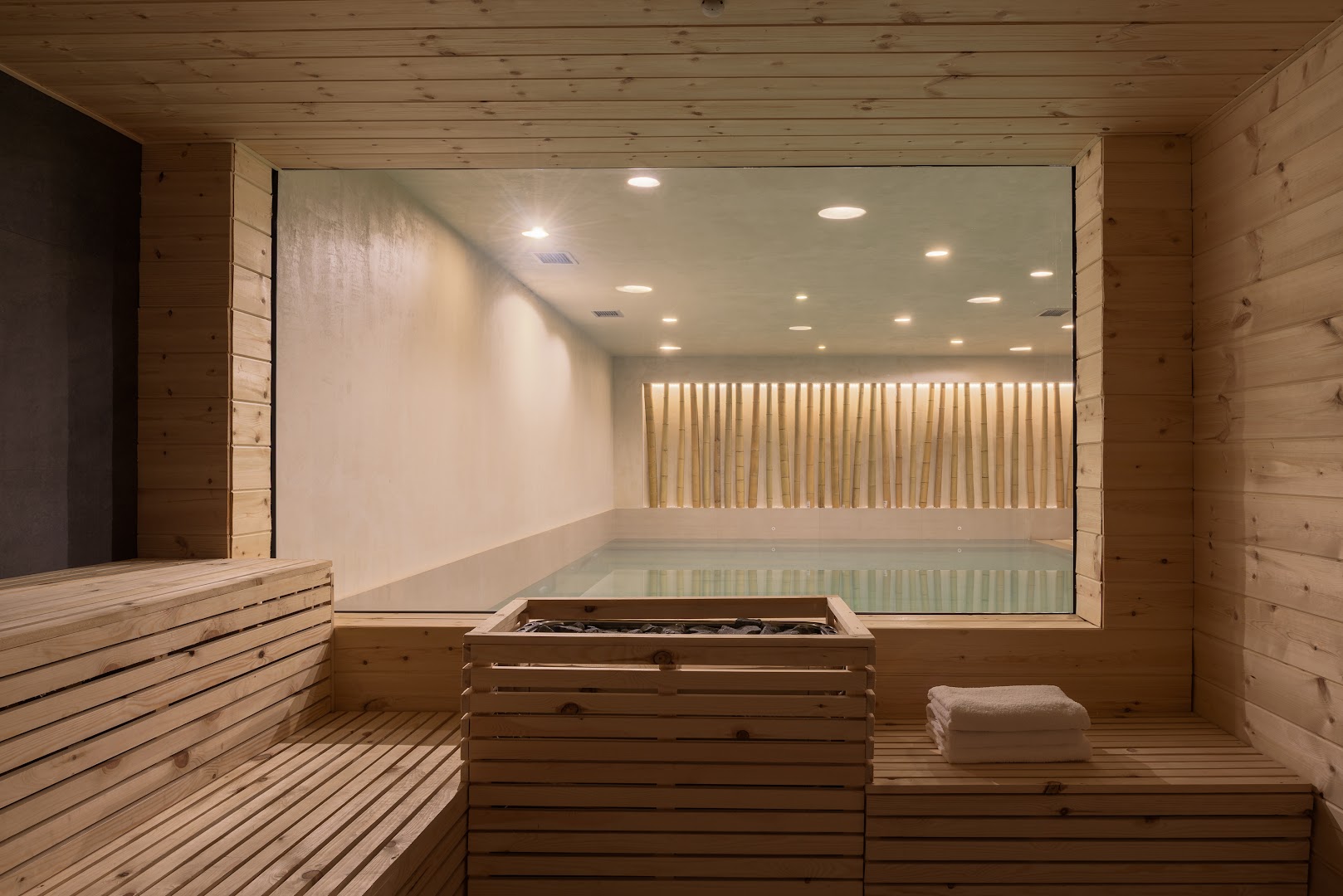 BIO Suites Hotel & Spa spa zona ar koka apdares saunu un skatu caur stiklu uz iekštelpu baseinu.