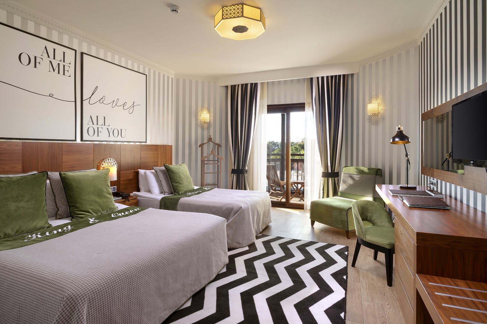 Selectum Family Resort Belek gaišs numurs ar divām gultām, koka mēbelēm, zaļiem atpūtas krēsliem un balkonu Belekā.