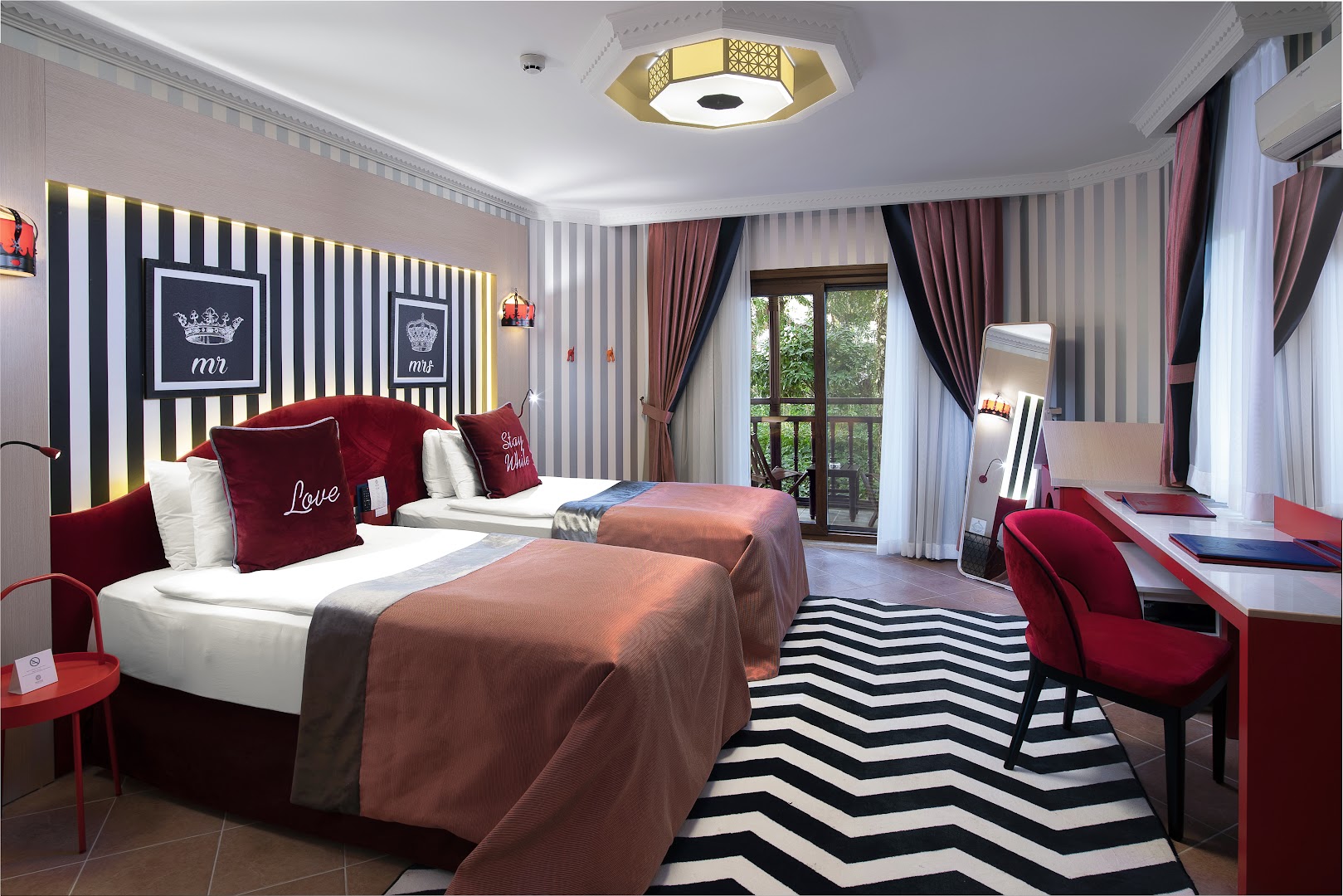 Selectum Family Resort Belek mājīgs numurs ar divām gultām, sarkanu interjeru, rakstāmgaldu un balkonu ar skatu uz dārzu Belekā.