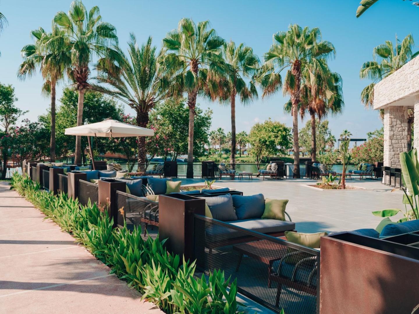 Selectum Family Resort Belek āra terase ar mīkstajiem dīvāniem, palmām un skatu uz upi vai kanālu Belekas reģionā