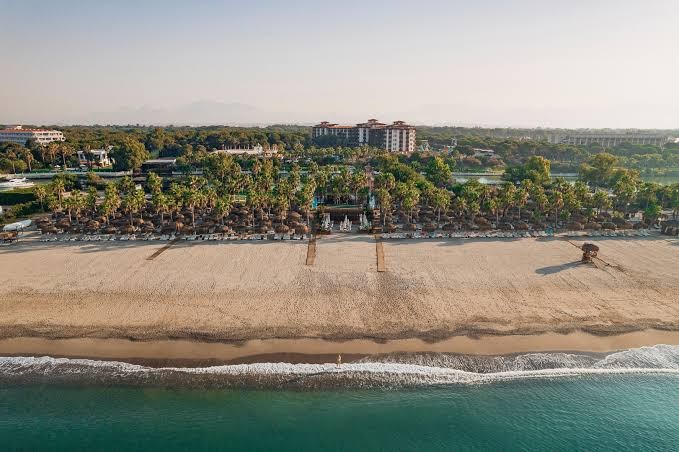 Selectum Family Resort Belek panorāmas skats no putna lidojuma uz plašo pludmali, viesnīcas ēkām un zaļo teritoriju Belekas piekrastē